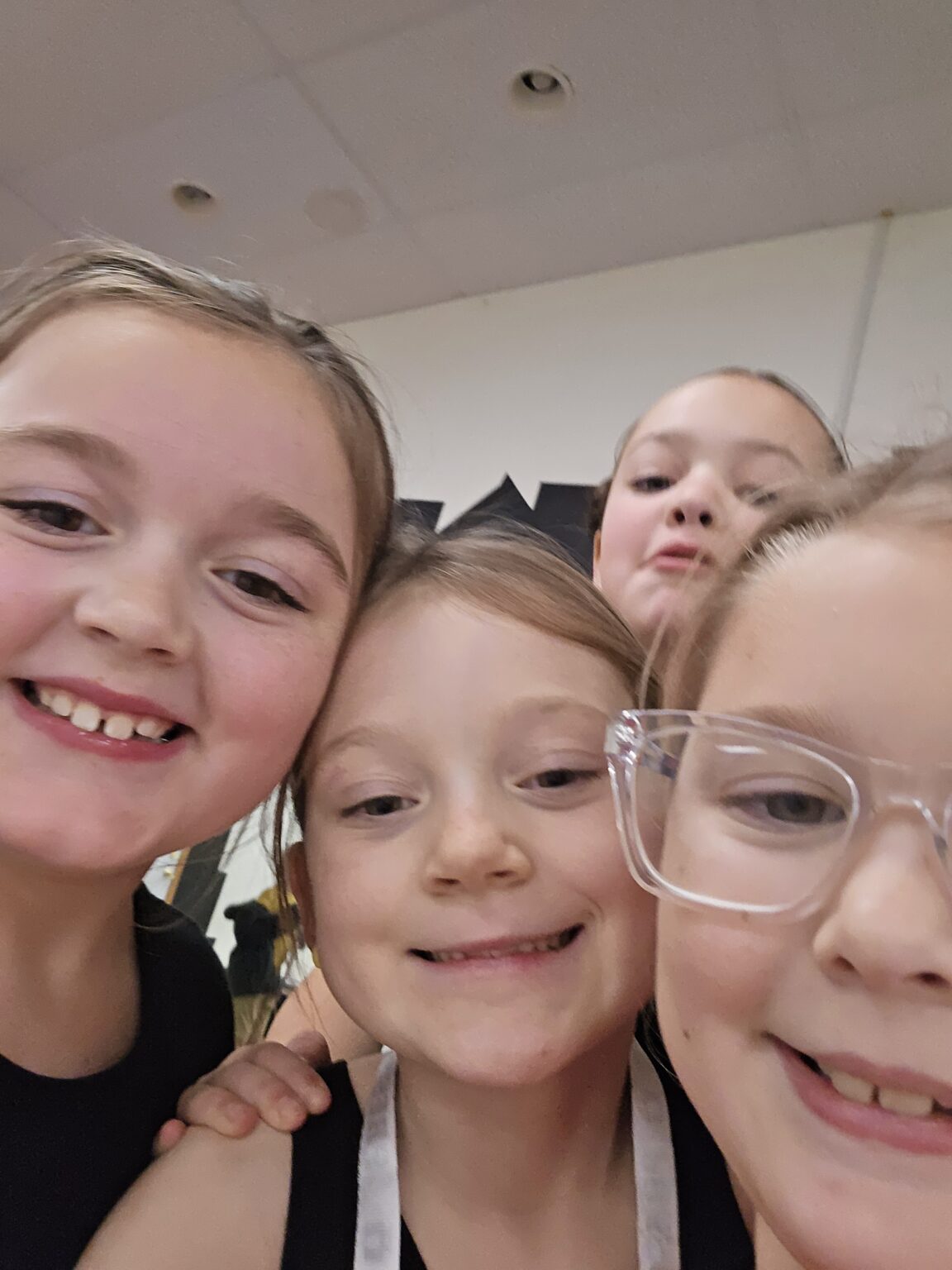 Four students smiling closely together backstage at the studio